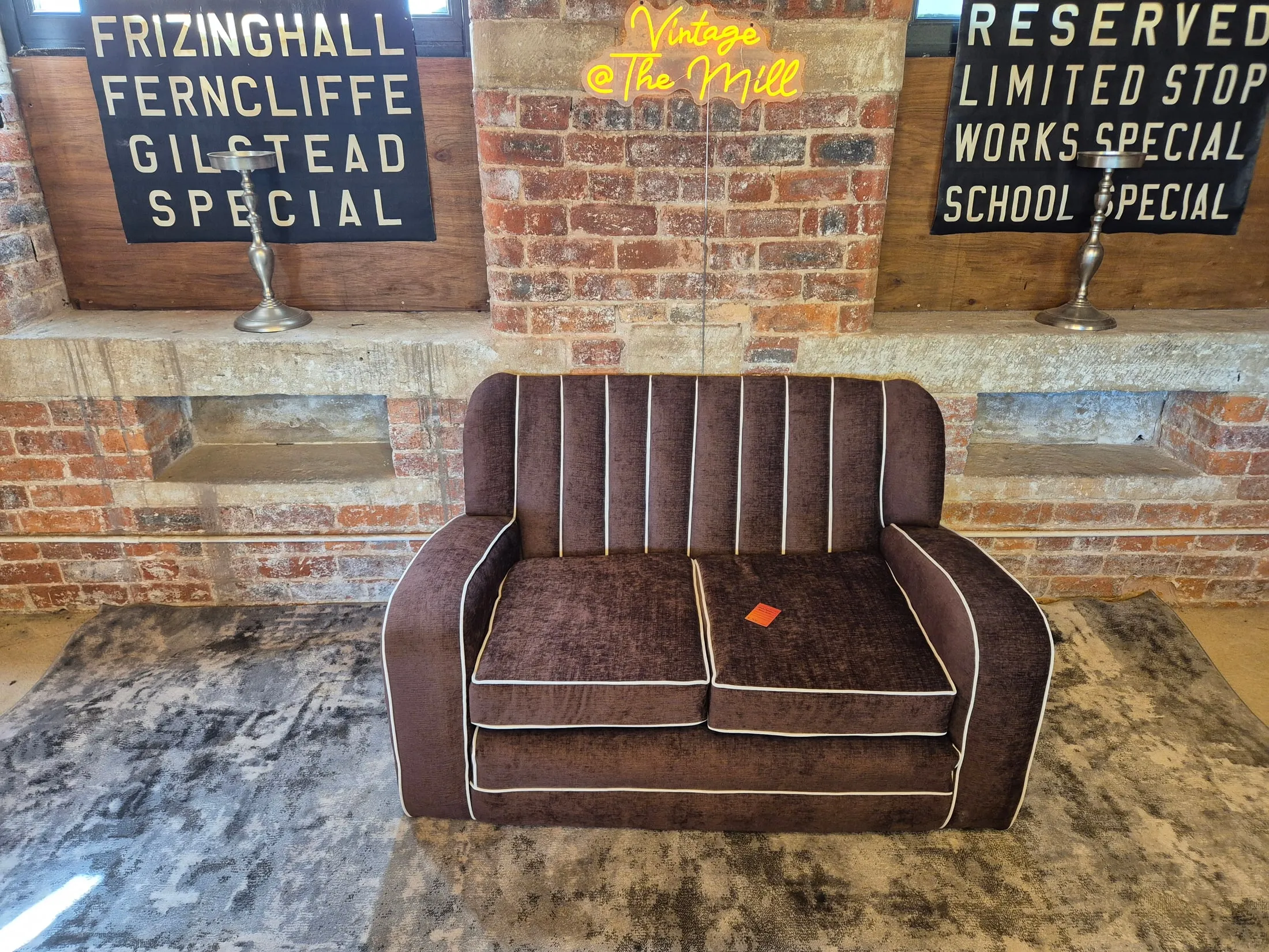 Brown curved-arm two-seater loveseat with piped cushions at Scandex, Cullingworth Mills.
